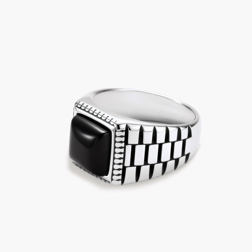 Silver stainless steel signet ring with checkered band texture, beaded border, and square black onyx cabochon stone center.